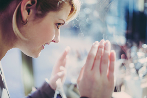 Young woman looking into shopping window.